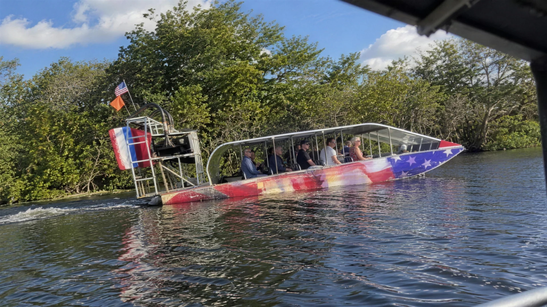 Stars-and-stripes airboat with guests on the water